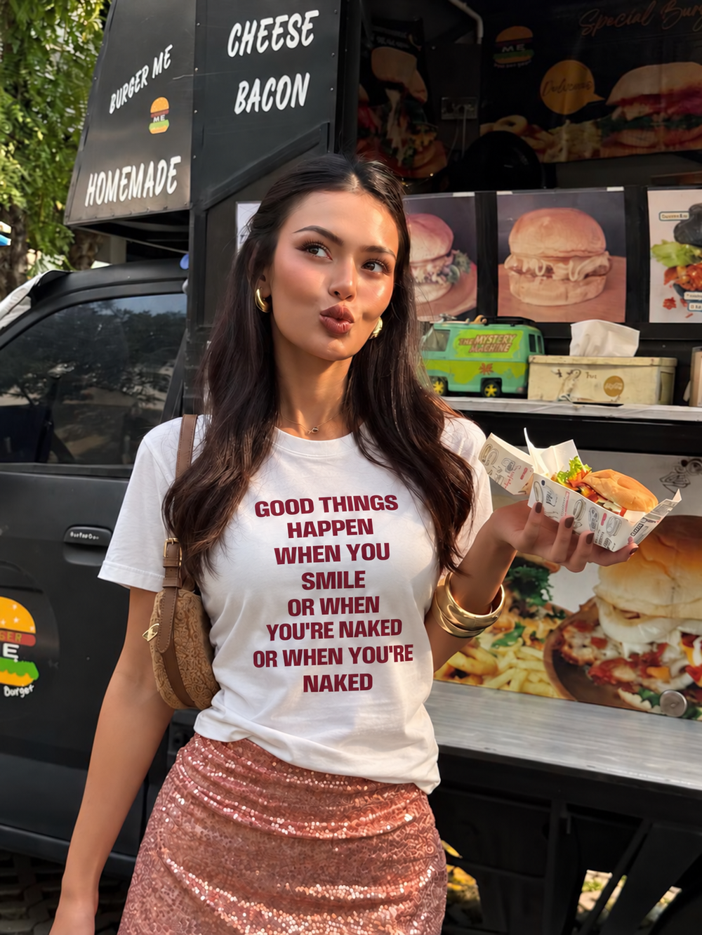 Woman wearing a white Good Things slogan T-shirt beside a food truck