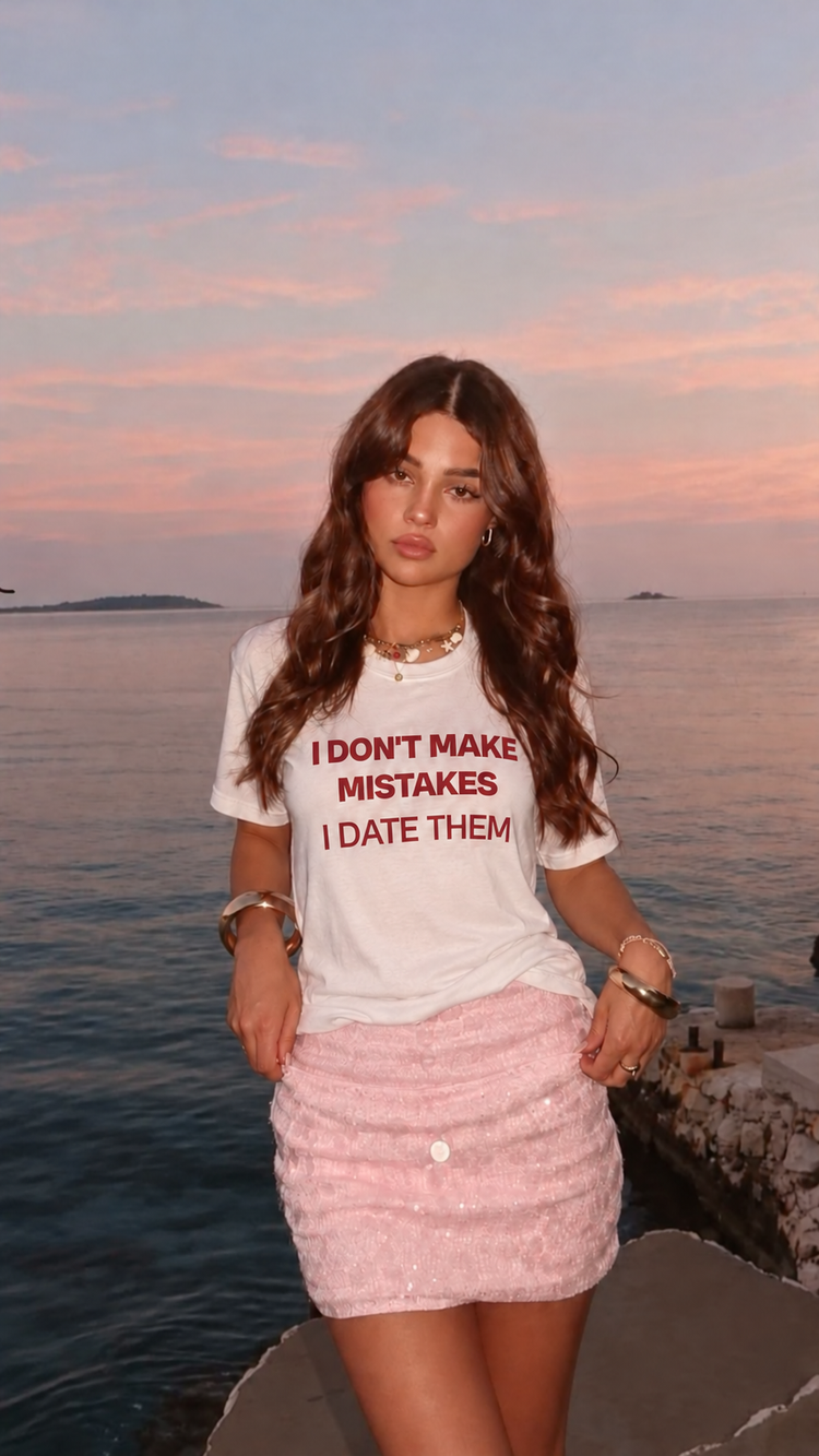 Woman wearing a white I Date Them slogan T-shirt by the sea at sunset