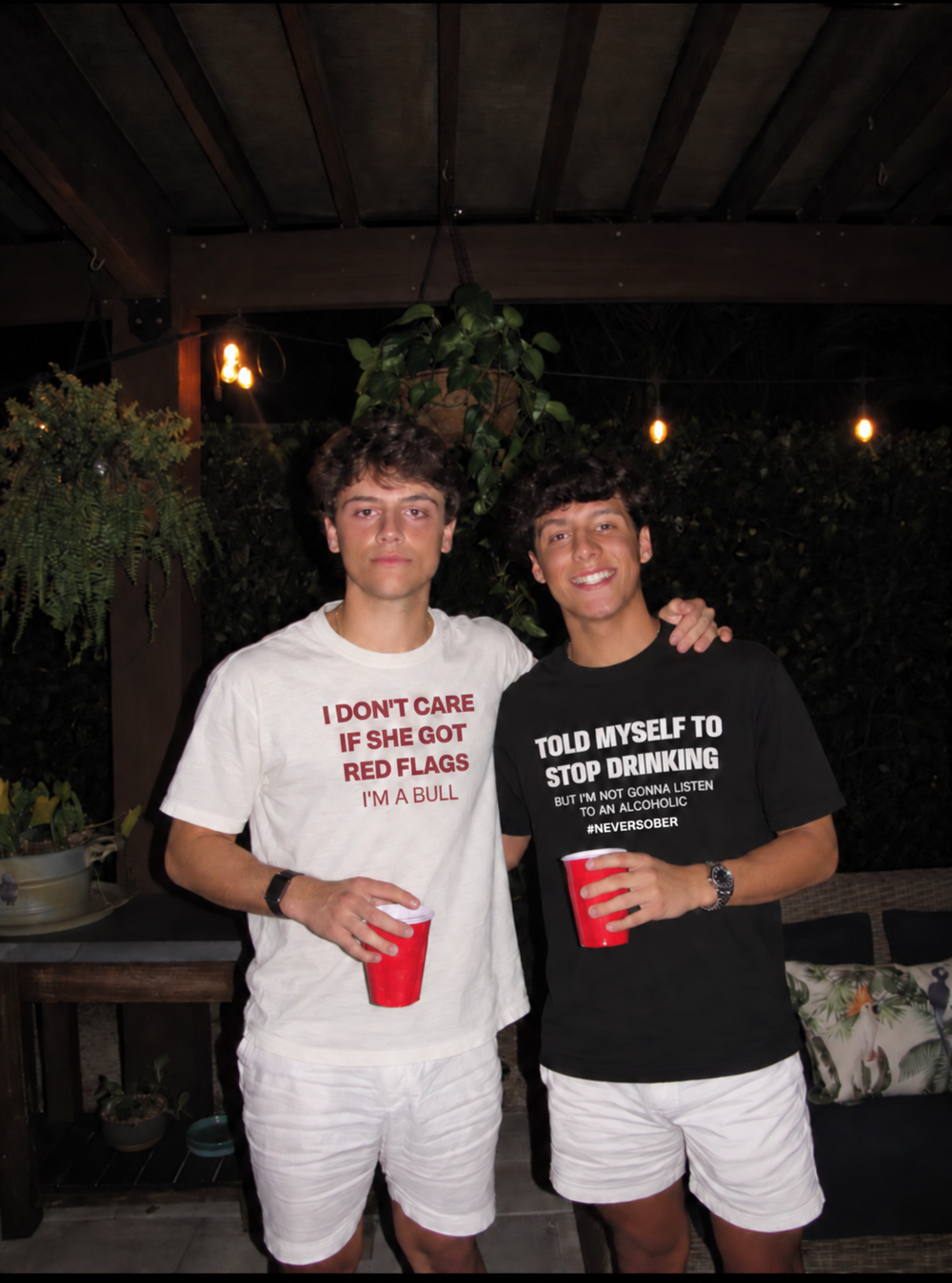 Two friends wearing white and black slogan T-shirts at night