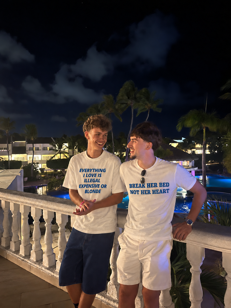 Two men wearing white slogan T-shirts at a resort at night